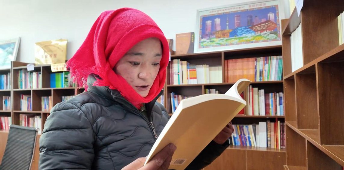 一名婦女正在認真閱讀書籍。申扎縣融媒體中心供圖