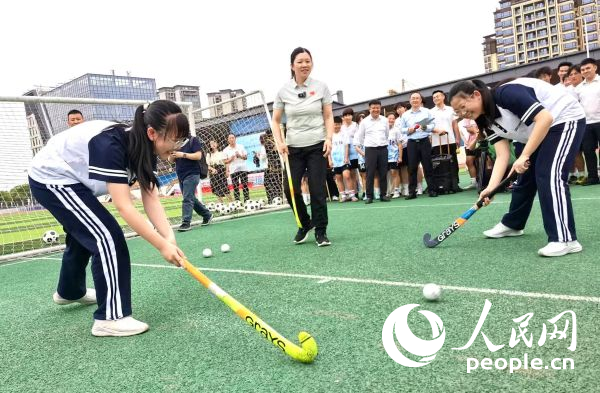 陈朝霞（中）指导学生体验曲棍球。 人民网记者 杨磊摄