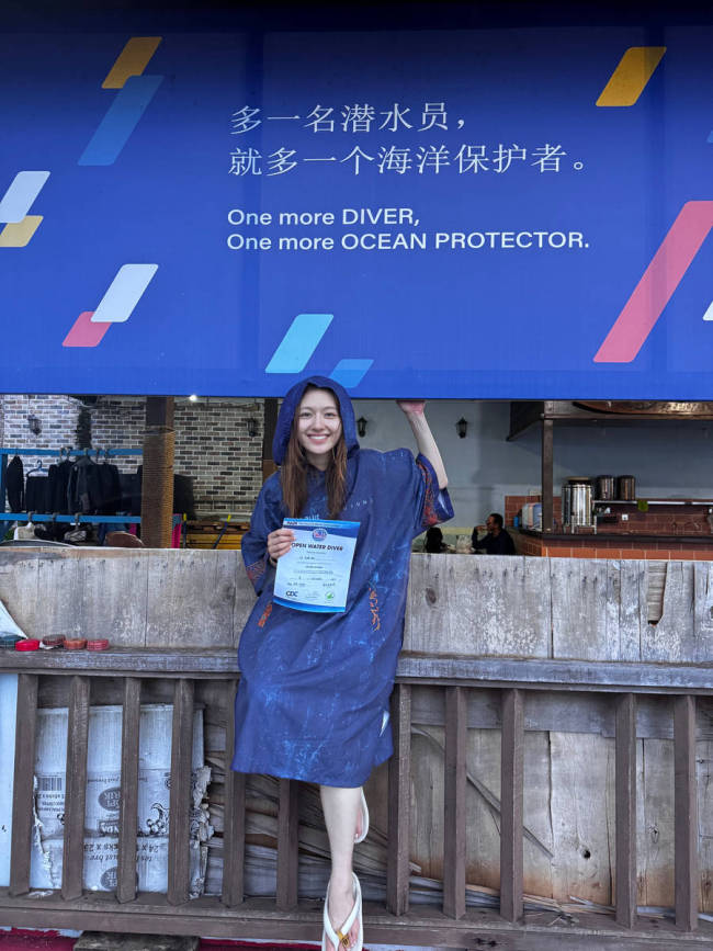 李兰迪拿着潜水证笑容灿烂 坐在海边素颜清秀