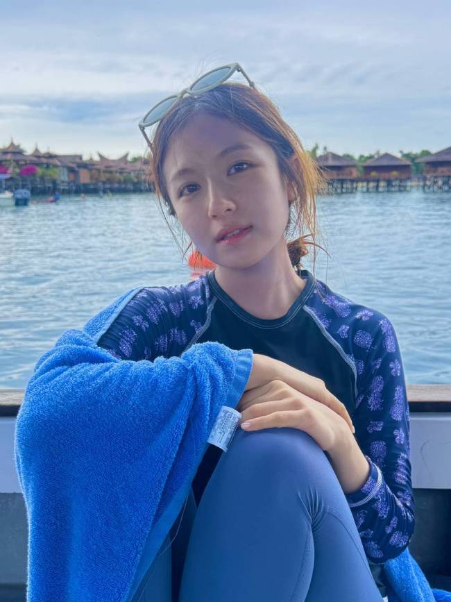 李兰迪拿着潜水证笑容灿烂 坐在海边素颜清秀