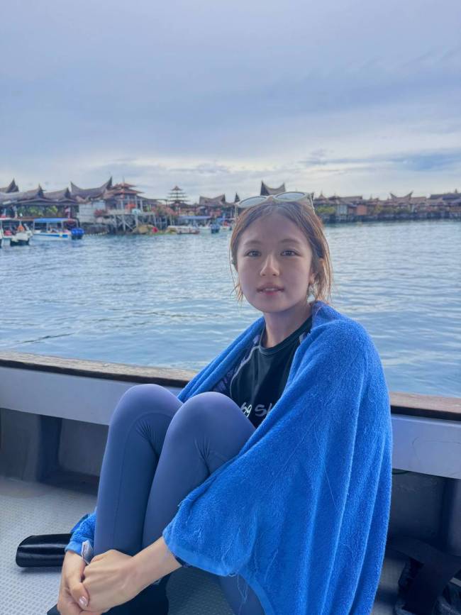 李兰迪拿着潜水证笑容灿烂 坐在海边素颜清秀